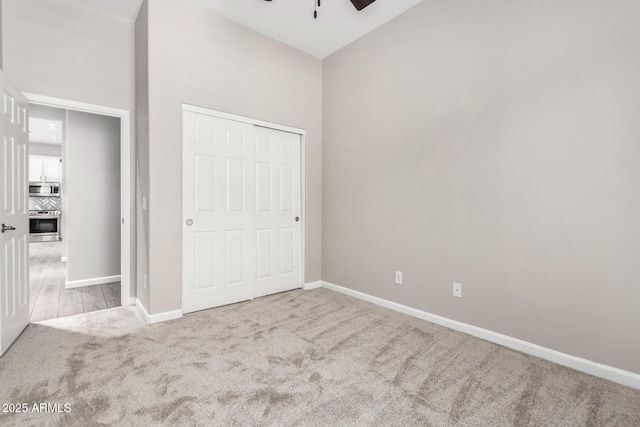 2409 W Red Range Way, Phoenix, AZ 85085 - unfurnished bedroom featuring carpet floors, baseboards, a closet, a ceiling fan, and a towering ceiling
