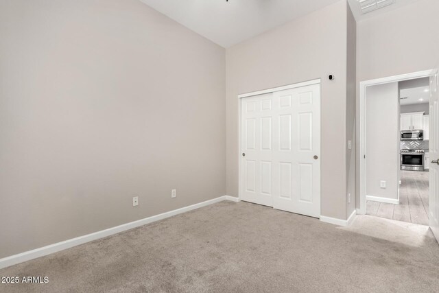 2409 W Red Range Way, Phoenix, AZ 85085 - unfurnished bedroom with light carpet, baseboards, a high ceiling, and a closet