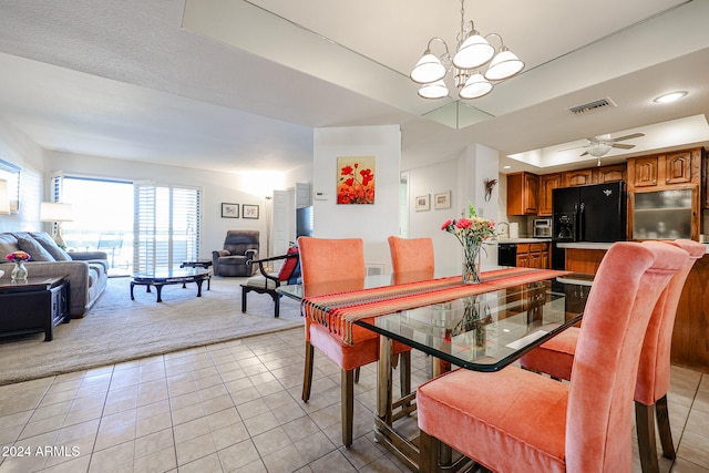 dining room featuring ceiling fan with notable chandelier, a raised ceiling, and light tile patterned floors