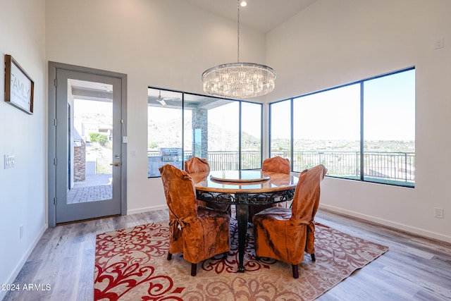 dining area featuring light wood-type flooring, an inviting chandelier, and high vaulted ceiling