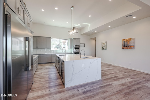 kitchen with light wood-type flooring, stainless steel appliances, a spacious island, and sink