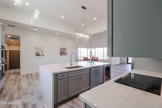 kitchen with sink, stainless steel dishwasher, pendant lighting, light hardwood / wood-style floors, and gray cabinets