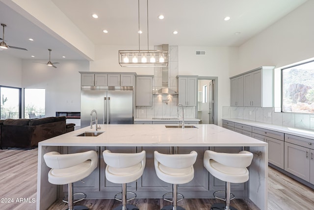 kitchen with decorative backsplash, a spacious island, built in fridge, and sink