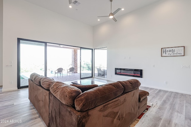 living room with a high ceiling, light hardwood / wood-style floors, and ceiling fan