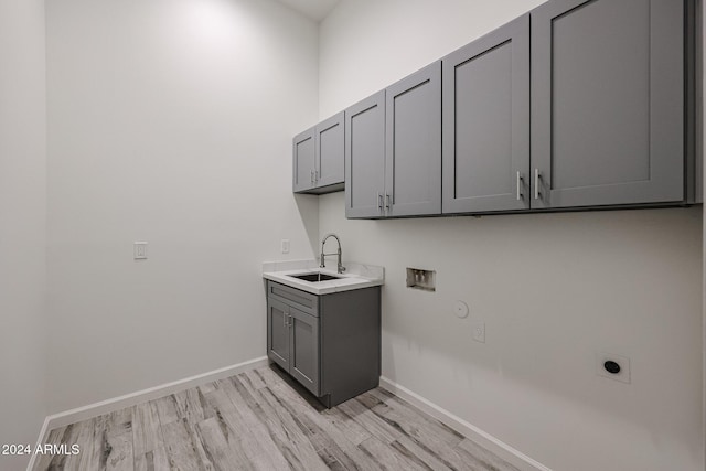 washroom featuring sink, washer hookup, cabinets, hookup for an electric dryer, and light wood-type flooring