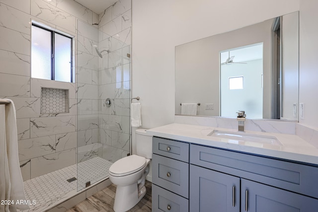 bathroom featuring vanity, wood-type flooring, ceiling fan, toilet, and a shower with shower door