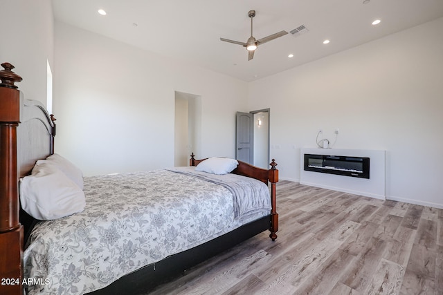 bedroom featuring a high ceiling, light hardwood / wood-style floors, and ceiling fan