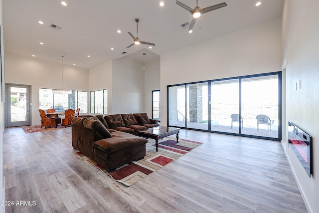 living room with a wealth of natural light, a high ceiling, and light wood-type flooring