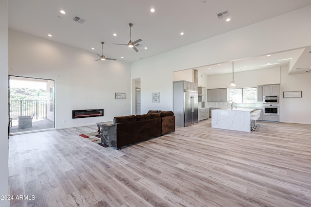 14914 E Zapata Dr, Fountain Hills, AZ 85268 - living room with a towering ceiling, ceiling fan, light wood-style floors, recessed lighting, and a glass covered fireplace