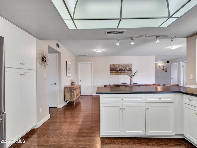 kitchen with dark countertops, white cabinets, and visible vents