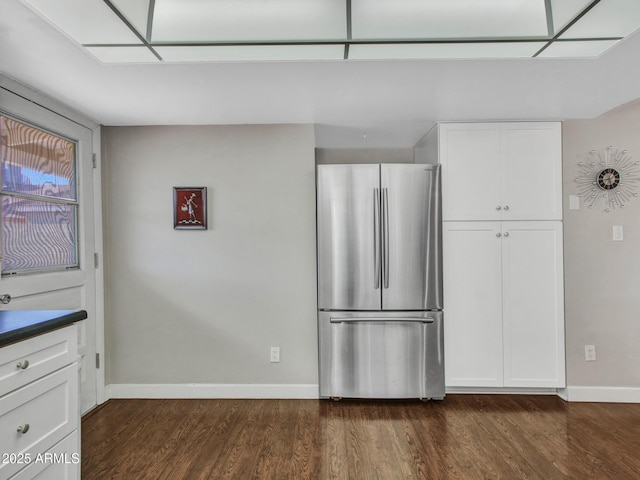 kitchen with baseboards, white cabinets, dark countertops, dark wood-style flooring, and freestanding refrigerator