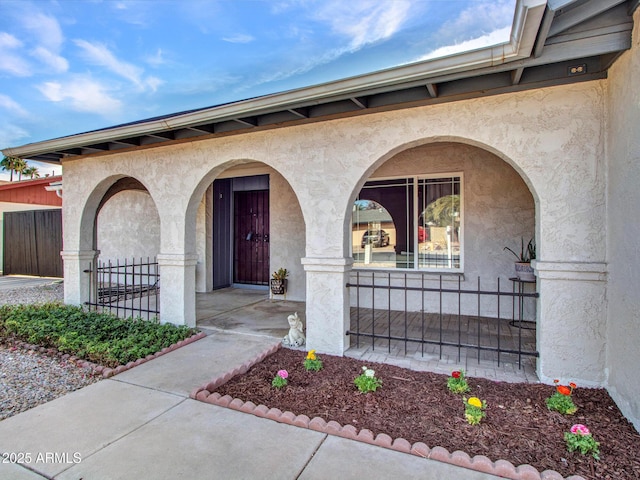 entrance to property with fence and stucco siding