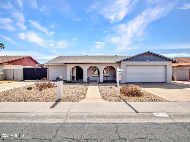 ranch-style home featuring a garage, driveway, a shingled roof, and fence