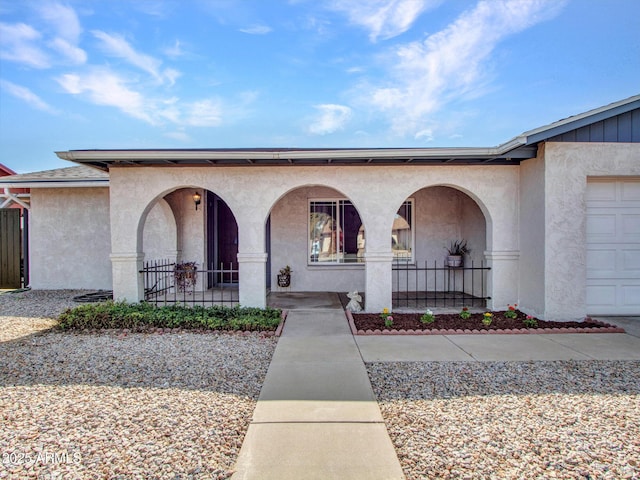 entrance to property with a garage, covered porch, and stucco siding