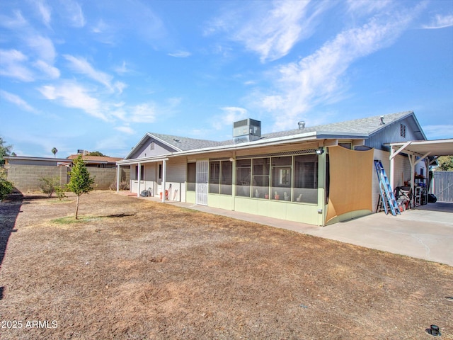 rear view of house featuring a yard, concrete driveway, a sunroom, central AC, and a carport