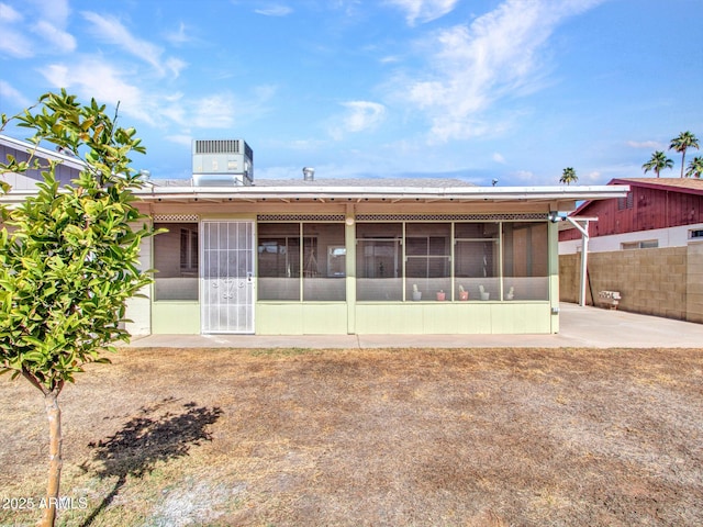 back of property with a sunroom, a patio area, fence, and central AC