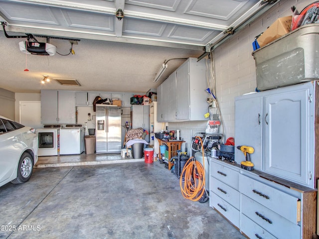 garage featuring stainless steel refrigerator with ice dispenser, washing machine and clothes dryer, concrete block wall, and a garage door opener