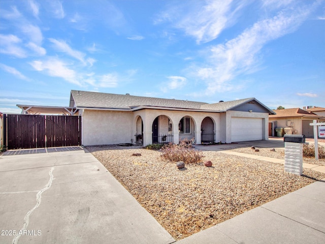 view of front of property featuring a garage, concrete driveway, fence, and stucco siding