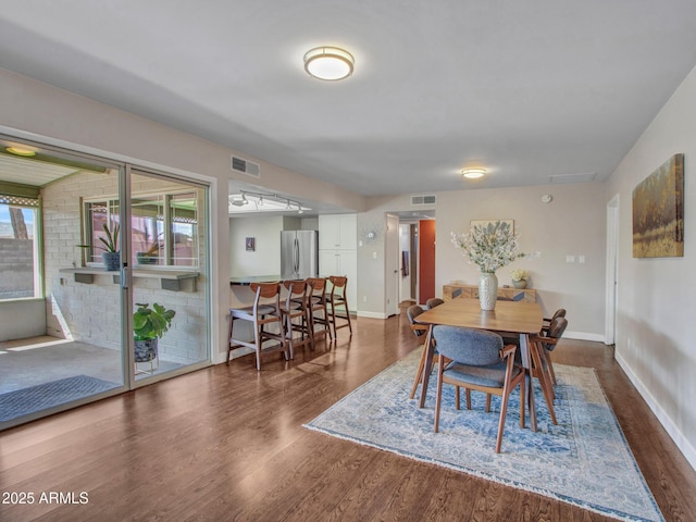 dining area featuring dark wood-type flooring, visible vents, and baseboards