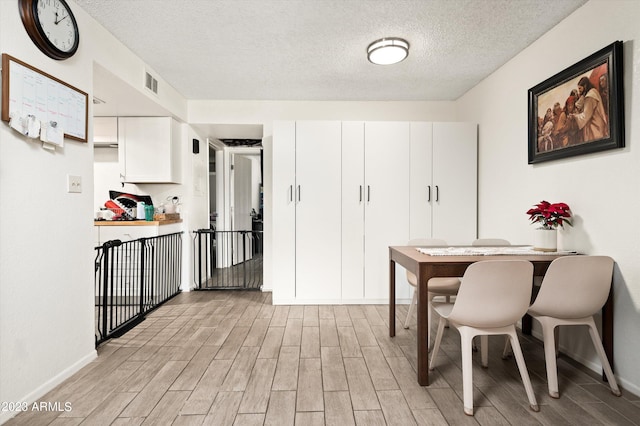 kitchen with light hardwood / wood-style flooring, white cabinets, and a textured ceiling