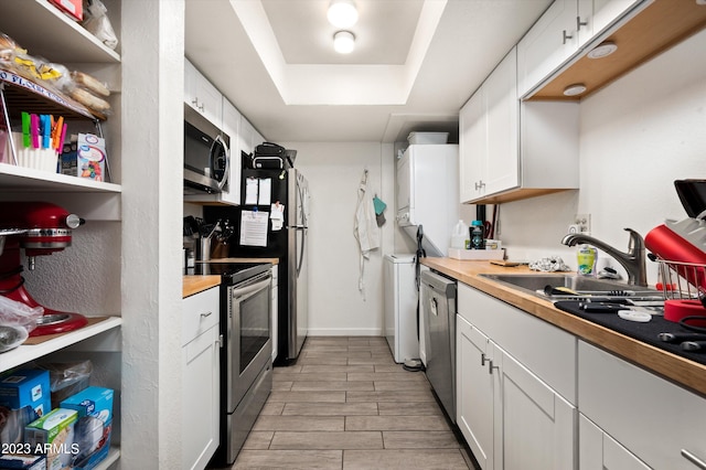 kitchen featuring stainless steel appliances, white cabinets, and a tray ceiling