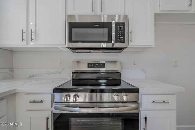 kitchen with white cabinets, light stone countertops, and appliances with stainless steel finishes