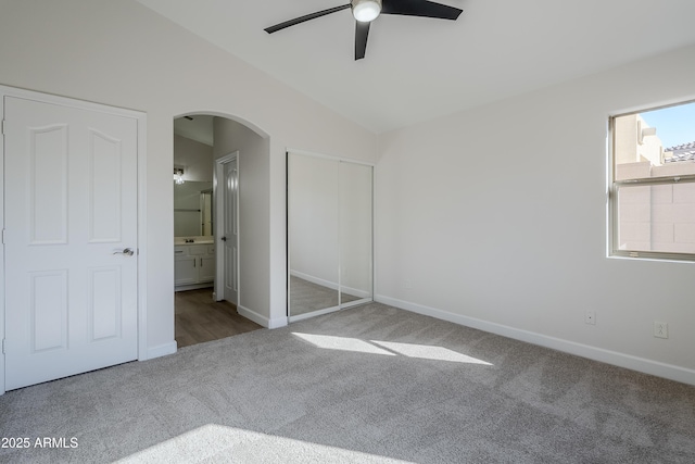 unfurnished bedroom featuring carpet flooring, ceiling fan, lofted ceiling, and ensuite bath