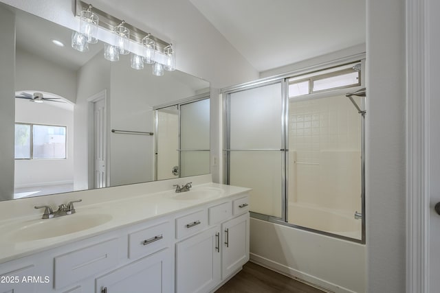 bathroom with hardwood / wood-style floors, vanity, combined bath / shower with glass door, vaulted ceiling, and ceiling fan