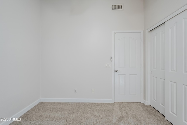 unfurnished bedroom featuring light carpet and a closet