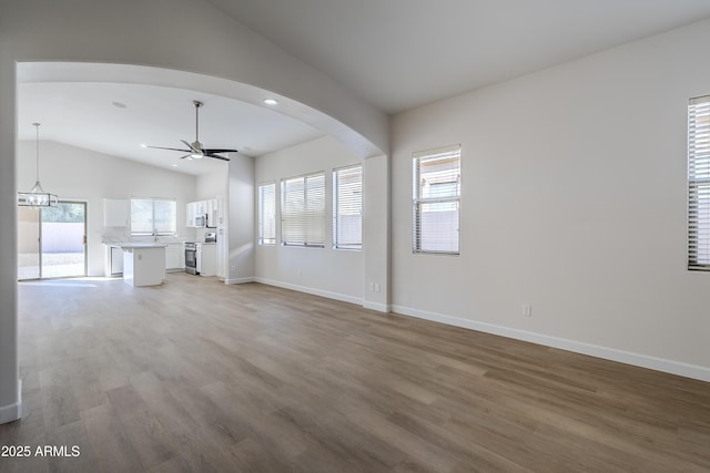 unfurnished living room with ceiling fan with notable chandelier, hardwood / wood-style flooring, and lofted ceiling