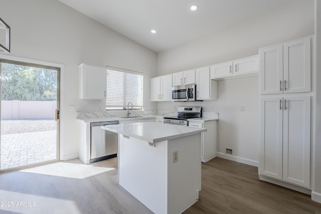 kitchen with sink, appliances with stainless steel finishes, plenty of natural light, a kitchen island, and white cabinetry