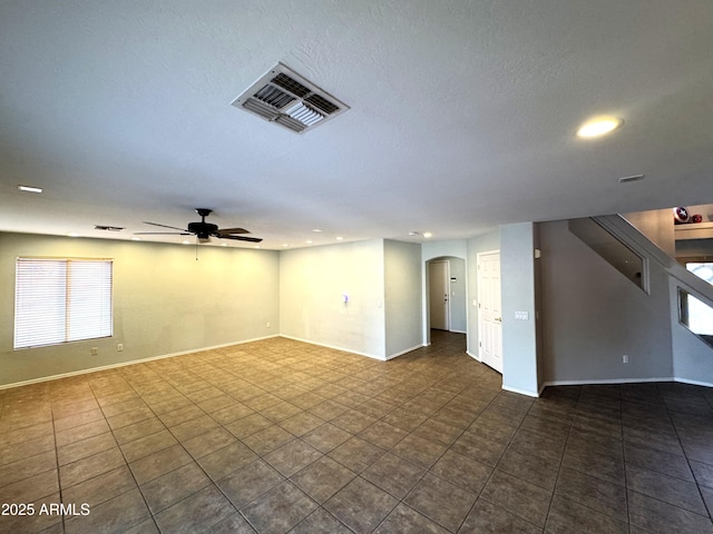 spare room with baseboards, visible vents, arched walkways, and a ceiling fan