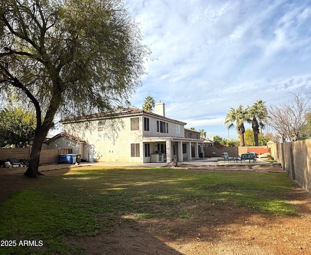 back of property with a chimney, stucco siding, a lawn, a patio area, and a fenced backyard