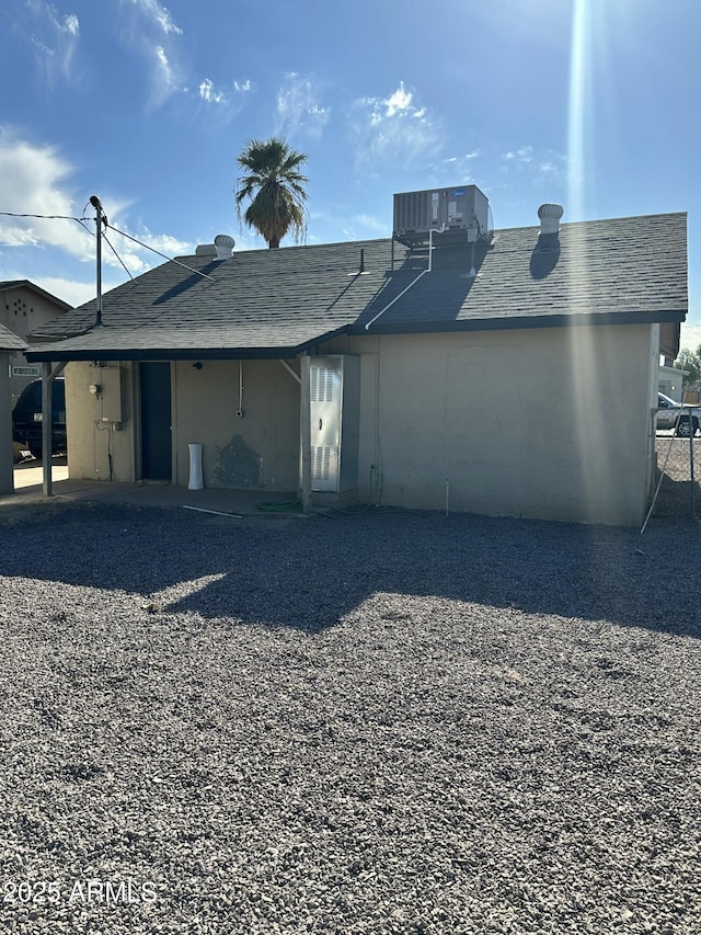 back of property featuring a shingled roof and central AC