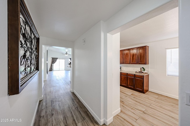 hall with lofted ceiling and light hardwood / wood-style flooring