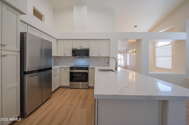 866 W Geronimo St, Chandler, AZ 85225 - kitchen with appliances with stainless steel finishes, a sink, light wood-style floors, a peninsula, and tasteful backsplash