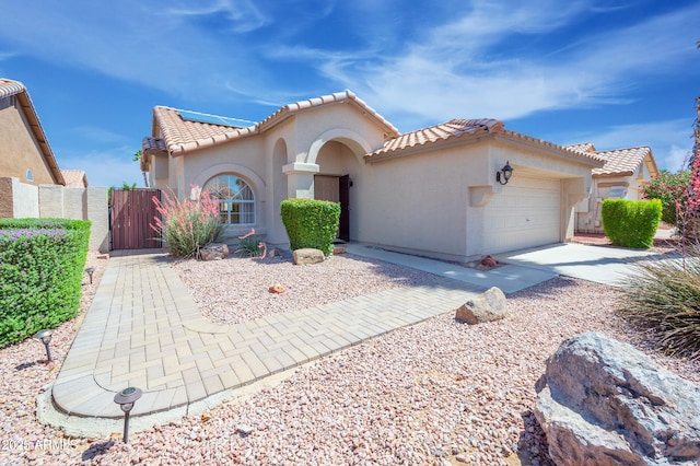 866 W Geronimo St, Chandler, AZ 85225 - mediterranean / spanish-style house featuring a gate, a garage, a tiled roof, stucco siding, and roof mounted solar panels