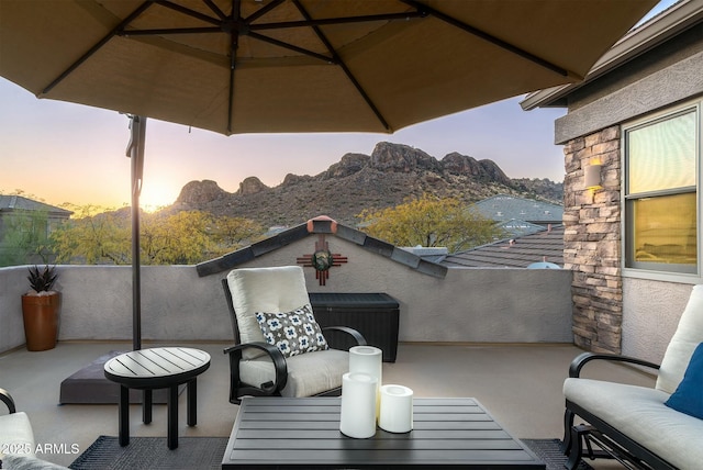 patio terrace at dusk with a mountain view and a balcony