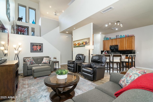 living room featuring a chandelier, light hardwood / wood-style flooring, and a high ceiling