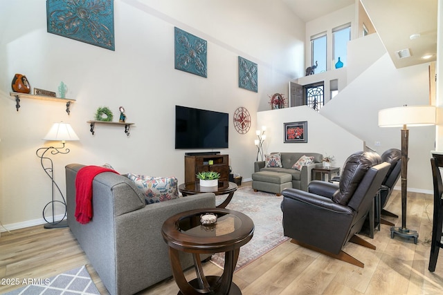 living room with a towering ceiling and light hardwood / wood-style floors