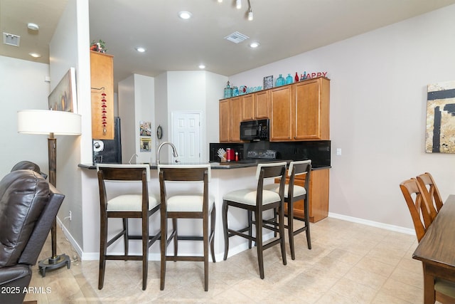 kitchen with tasteful backsplash, sink, a breakfast bar area, and kitchen peninsula