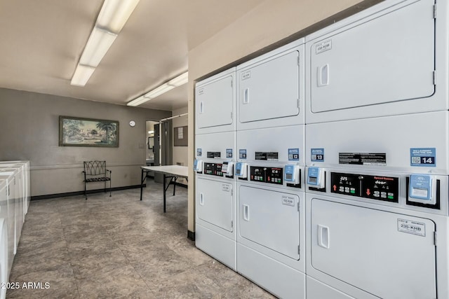 shared laundry area with stacked washing maching and dryer, washing machine and clothes dryer, and baseboards