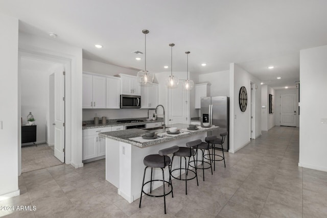 kitchen featuring pendant lighting, white cabinetry, a kitchen island with sink, and appliances with stainless steel finishes