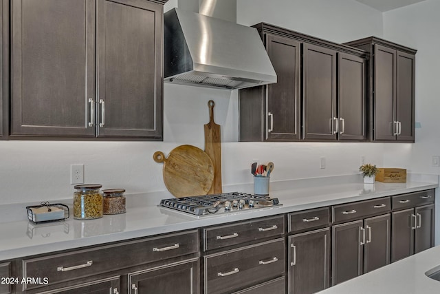 kitchen featuring stainless steel gas stovetop, wall chimney range hood, and dark brown cabinetry