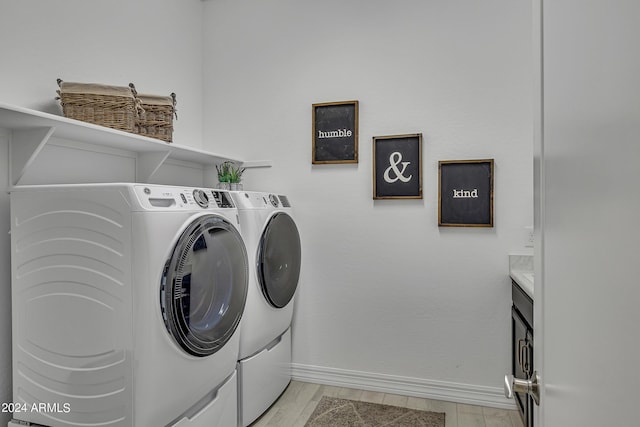 clothes washing area with washer and dryer and light wood-type flooring