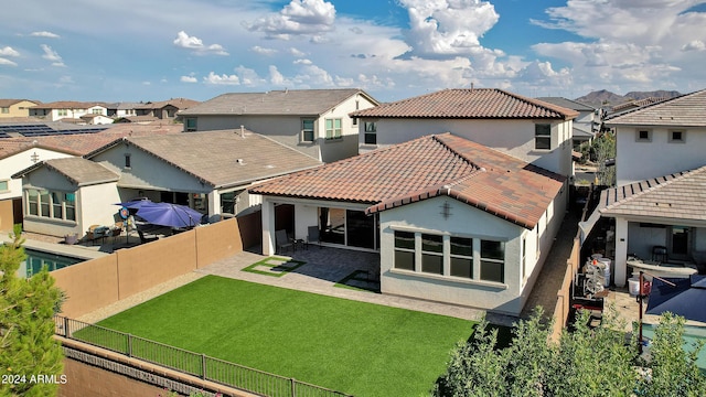 rear view of property featuring a yard and a patio area