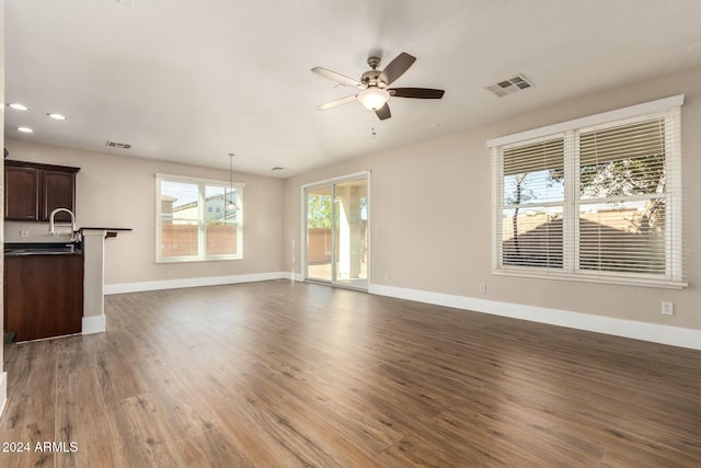 unfurnished living room with ceiling fan, sink, and dark hardwood / wood-style floors