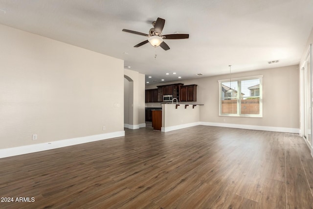 unfurnished living room featuring ceiling fan, dark wood-type flooring, and sink