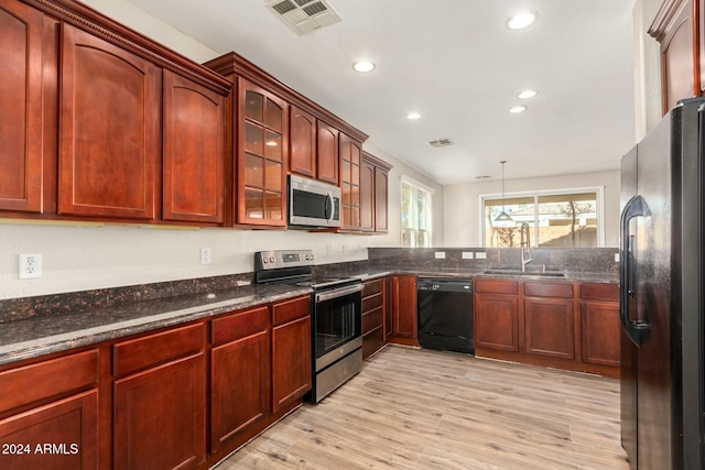 kitchen featuring black appliances, decorative light fixtures, light wood-type flooring, and sink