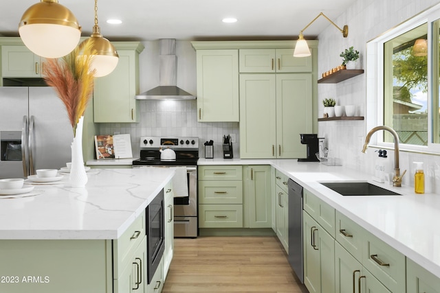 kitchen with pendant lighting, backsplash, wall chimney range hood, sink, and stainless steel appliances